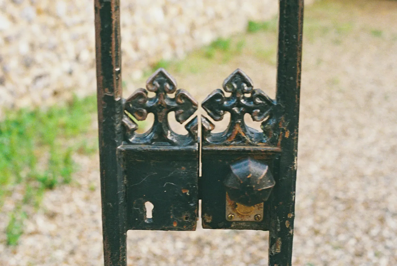 Close view of a black wrought iron gate latch with a keyhole