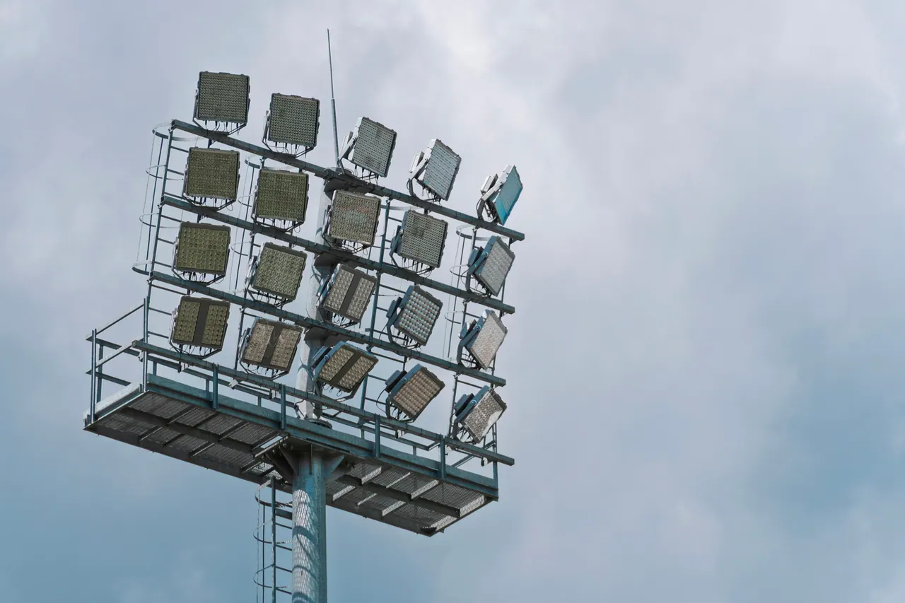 A stadium floodlight tower against a soft gray sky